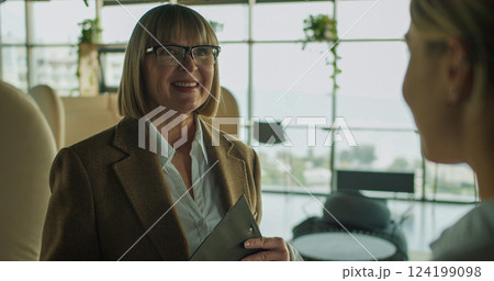 Smiling businesswoman holding a clipboard during a positive discussion in a modern office setting, showcasing confidence, teamwork, and professional interaction Smiling businesswoman holding a clipboard during a positive discussion in a modern office setting, showcasing confidence, teamwork, and professional interaction 124199098