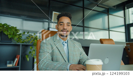 Confident businessman smiling while working in a modern office setting. 124199103