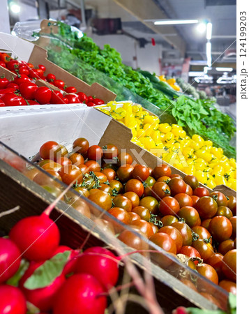 Various type of fresh fruits arrange neatly, grocery store. Radishes, tomatoes, yellow peppers, green vegetables on rack.  124199203