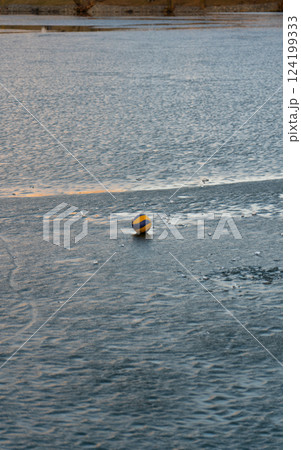 Volleyball ball on the river ice. The ball on the ice. A ball on the water 124199333