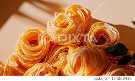 Close-up of fresh tagliatelle pasta nests, showcasing vibrant yellow color, raw texture, and rustic Italian culinary preparation on a neutral background 124200416