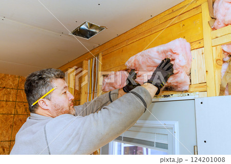 Contractor adds energy efficiency insulation to home walls during renovation for energy efficiency comfort. 124201008