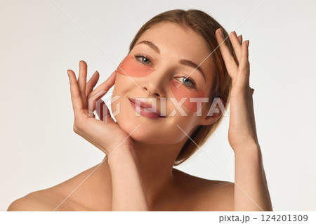 Portrait of attractive, happy, young woman with glowing, healthy skin, posing with under eye patches against white background Portrait of attractive, happy, young woman with glowing, healthy skin, posing with under eye patches against white background 124201309