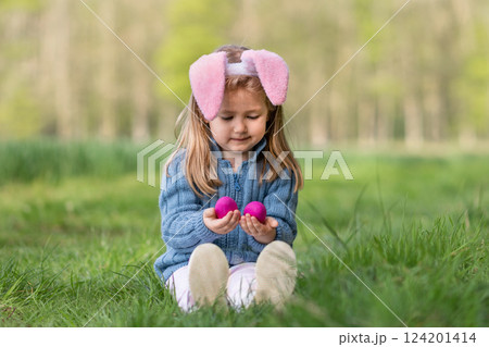 Girl with bunny ears collects the eggs for Easter 124201414