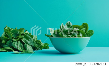 A bowl filled with green leaves sits atop a blue counter 124202161