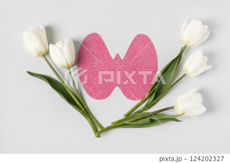 World Thyroid Day. Concept of thyroid disease and health. Pink Paper form of the thyroid gland on gray background with spring white and white flowers tulips World Thyroid Day. Concept of thyroid disease and health. Pink Paper form of the thyroid gland on gray background with spring white and white flowers tulips 124202327
