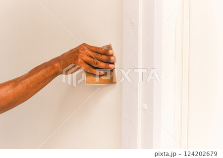 Worker hand polishing a wall with sandpaper. Worker hand polishing a wall with sandpaper. 124202679