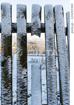 Wooden fence covered with snow, close-up. 124203304