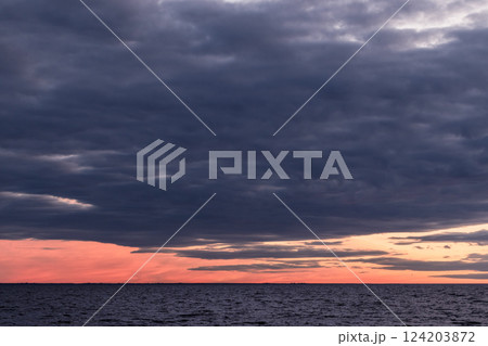 Dramatic sunset over a calm ocean with vibrant colors and extensive clouds Dramatic sunset over a calm ocean with vibrant colors and extensive clouds 124203872