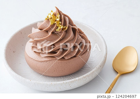 Decadent chocolate mousse topped with gold flakes served in a white ceramic bowl Decadent chocolate mousse topped with gold flakes served in a white ceramic bowl 124204697