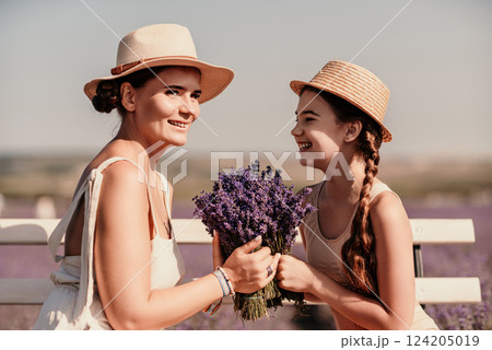 A woman and a child are sitting on a bench in a field of purple flowers lavande. The woman is holding a bouquet of flowers and the child is holding a bouquet of flowers as well A woman and a child are sitting on a bench in a field of purple flowers lavande. The woman is holding a bouquet of flowers and the child is holding a bouquet of flowers as well 124205019