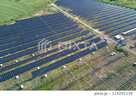 Aerial view of big electric power plant under construction with many rows of solar panels on metal frame for producing clean electrical energy. Development of renewable electricity sources Aerial view of big electric power plant under construction with many rows of solar panels on metal frame for producing clean electrical energy. Development of renewable electricity sources 124205139