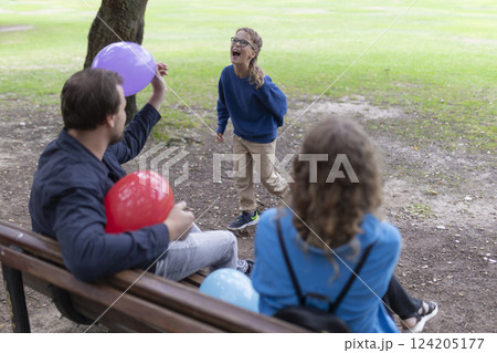 Happy family playing with balloons in park on bench 124205177