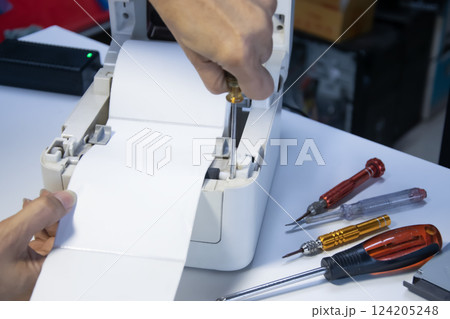 Top view. Technician repairing printer, label printer. Top view. Technician repairing printer, label printer. 124205248