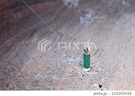 Close-up of burning incense in fine sand, with soft smoke rising into the air 124205438