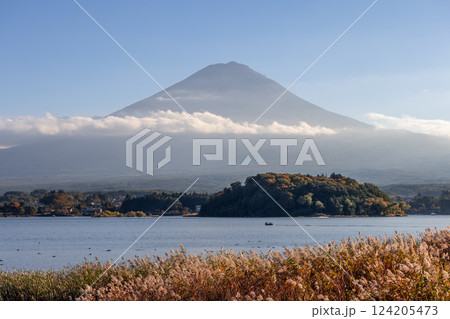 Mount Fuji rises above Lake Kawaguchi in Japan, partially covered by clouds during the golden hour 124205473