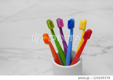 Six colored toothbrushes in a glass in the bathroom. Light photo. Place for text. Six colored toothbrushes in a glass in the bathroom. Light photo. Place for text. 124205579