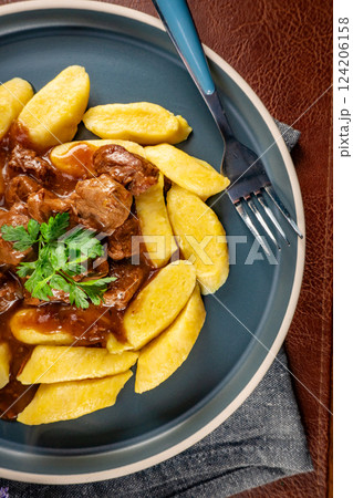Beef stew in gravy served with potato dumplings. 124206158