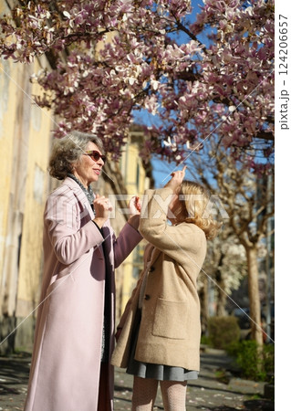 Grandmother and granddaughter enjoying magnolia blossoms outdoors Grandmother and granddaughter enjoying magnolia blossoms outdoors 124206657