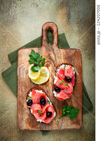 sandwiches with cream cheese, chum salmon, cold smoked, grain bread, on a cutting board, top view, breakfast, lemon and parsley, no people, sandwiches with cream cheese, chum salmon, cold smoked, grain bread, on a cutting board, top view, breakfast, lemon and parsley, no people, 124207008