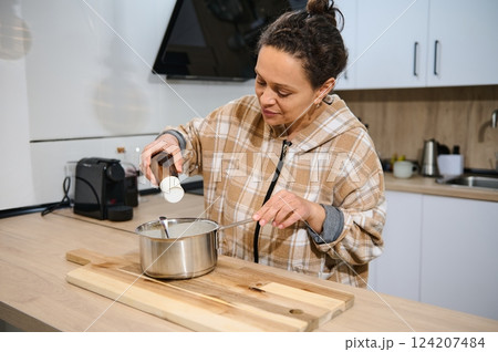 Woman Preparing a Dish With Ingredients in a Modern Home Kitchen 124207484