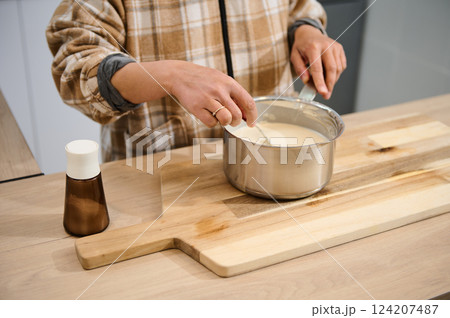 Woman Cooking in Kitchen With Batter on Wood Cutting Board 124207487