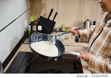Woman Cooking Crepe Batter on Stove in a Modern Home Kitchen 124207495