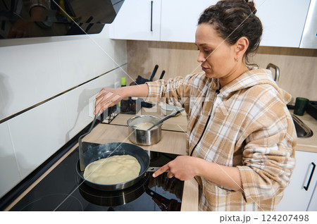 Woman Cooking Crepes on a Stove in a Bright Modern Kitchen Woman Cooking Crepes on a Stove in a Bright Modern Kitchen 124207498