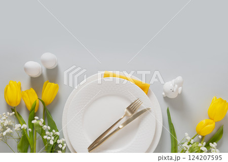 Easter frame with pastel yellow eggs, yellow tulips, gypsophila on gray background. View from above. Happy Easter greeting card. Easter frame with pastel yellow eggs, yellow tulips, gypsophila on gray background. View from above. Happy Easter greeting card. 124207595