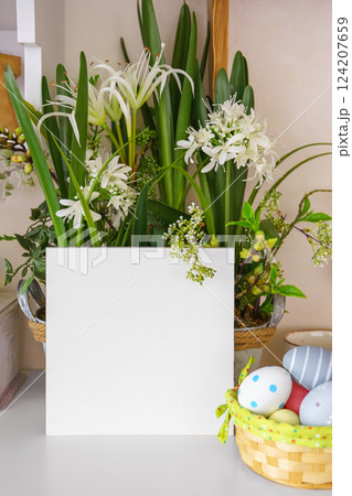 Beautiful vibrant flowers in decorative pot and Easter eggs with square empty display cardboard 124207659