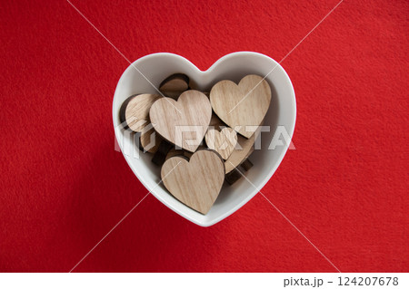 Much wood hearts in the plate on a red background with copyspace. Concept of Valentine's day and romantic love. Much wood hearts in the plate on a red background with copyspace. Concept of Valentine's day and romantic love. 124207678