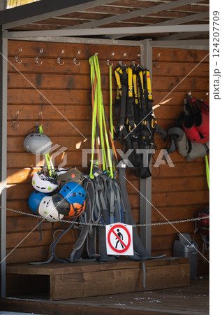Safety gear and equipment waiting for climbers at a mountain adventure site showcasing various helmets and harnesses in vibrant colors under natural light 124207709