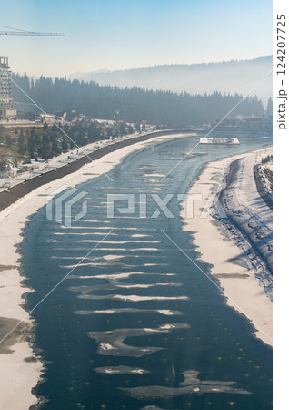 Winter serenity unfolds along a tranquil river surrounded by misty mountains and frosted trees in a peaceful landscape Winter serenity unfolds along a tranquil river surrounded by misty mountains and frosted trees in a peaceful landscape 124207725