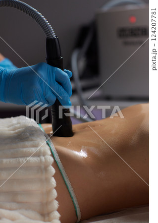 procedure removing cellulite on female abdomen, cavitation belly massage. Ultrasonic massage for weight loss. Correction of female figure without surgical intervention. Closeup of the tummy procedure removing cellulite on female abdomen, cavitation belly massage. Ultrasonic massage for weight loss. Correction of female figure without surgical intervention. Closeup of the tummy 124207781