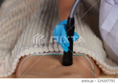 procedure removing cellulite on female abdomen, cavitation belly massage. Ultrasonic massage for weight loss. Correction of female figure without surgical intervention. Closeup of the tummy procedure removing cellulite on female abdomen, cavitation belly massage. Ultrasonic massage for weight loss. Correction of female figure without surgical intervention. Closeup of the tummy 124207791