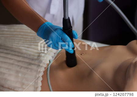 procedure removing cellulite on female abdomen, cavitation belly massage. Ultrasonic massage for weight loss. Correction of female figure without surgical intervention. Closeup of the tummy procedure removing cellulite on female abdomen, cavitation belly massage. Ultrasonic massage for weight loss. Correction of female figure without surgical intervention. Closeup of the tummy 124207798