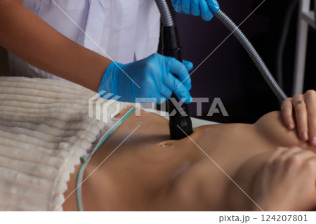 procedure removing cellulite on female abdomen, cavitation belly massage. Ultrasonic massage for weight loss. Correction of female figure without surgical intervention. Closeup of the tummy 124207801
