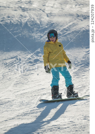 Snowboarding adventure of a young rider conquering the slopes under bright sunlight at a winter resort during a crisp afternoon 124207939