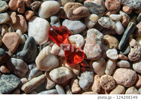 Two glass red bright heart on other stones near the river with sun weather. Two glass red bright heart on other stones near the river with sun weather. 124208149