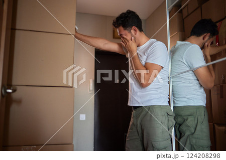 Man standing in living room on day of move to rented home, unbox carton box with belongings. Relocate to new own apartment collect personal things 124208298