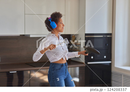 Overjoyed millennial girl wearing headphones have fun moving listening to music relax in living room, happy young woman in earphones dance enjoy leisure weekend at home, stress free concept 124208337