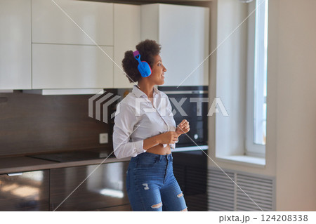 Overjoyed millennial girl wearing headphones have fun moving listening to music relax in living room, happy young woman in earphones dance enjoy leisure weekend at home, stress free concept 124208338