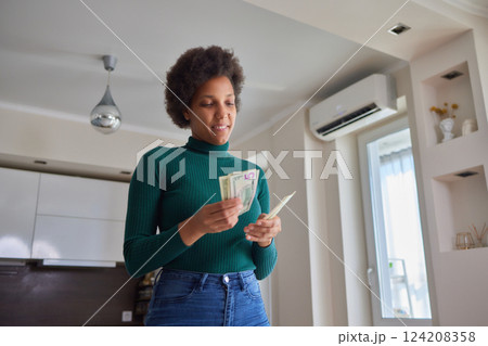 Attractive young African American woman working on finances at home wearing purple jacket sitting at dining table. 124208358