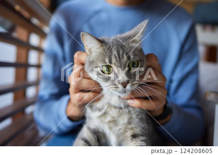 young man holding and petting cute cat male young man holding and petting cute cat male 124208605