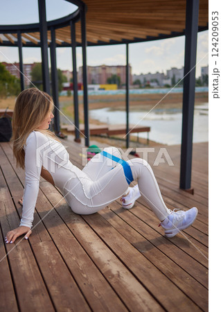 Sporty young woman during her fitness in an outdoor gym with rubber resistance band. 124209053