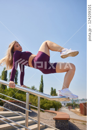 Portrait of fit and sporty young woman doing stretching in city. 124209101