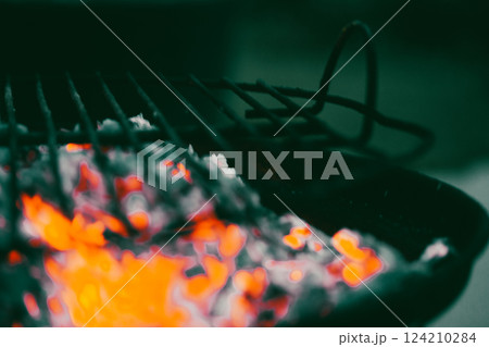 Smoldering wood on a metal barbecue grill. BBQ outdoors. Dangerous hot orange firewood. Fiery blaze. Cooking food on hot coals outside in nature. 124210284