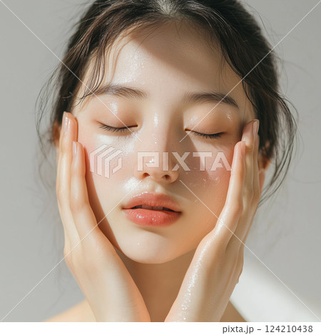 頬に触れて肌の質感を確かめる女性 124210438