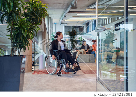 In a modern office, a young businesswoman in a wheelchair is surrounded by her supportive colleagues, embodying the spirit of inclusivity and diversity in the workplace In a modern office, a young businesswoman in a wheelchair is surrounded by her supportive colleagues, embodying the spirit of inclusivity and diversity in the workplace 124212091