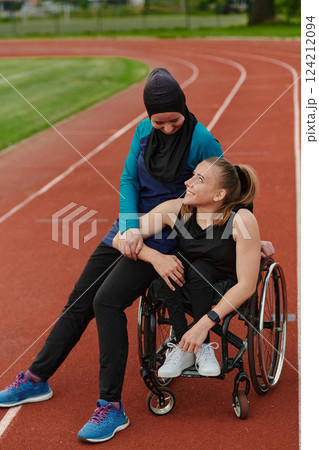 A Muslim woman wearing a burqa resting with a woman with disability after a hard training session on the marathon course A Muslim woman wearing a burqa resting with a woman with disability after a hard training session on the marathon course 124212094